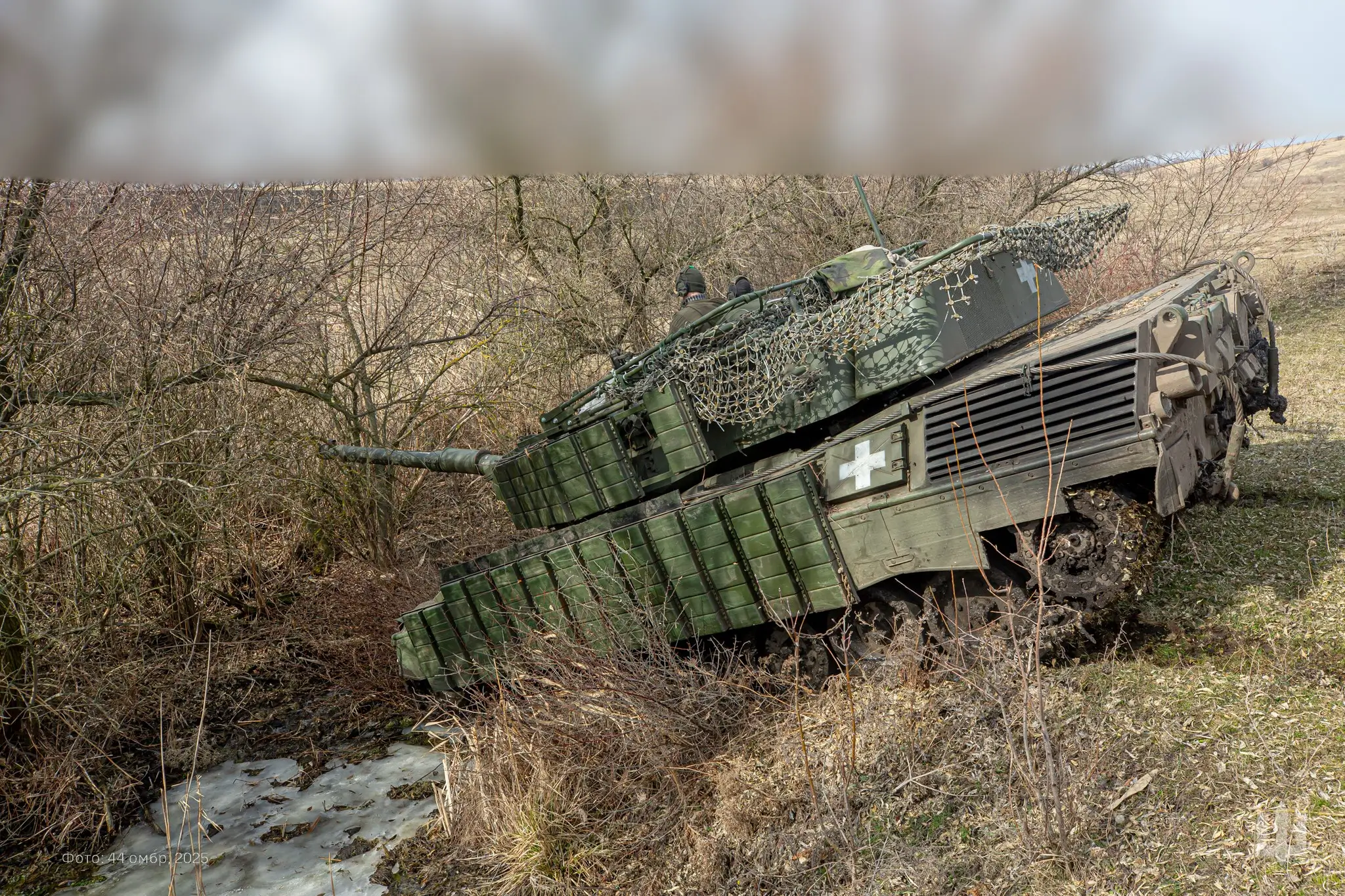 Leopard 1A5 with additional reactive armour and a drone cage drives through a ditch