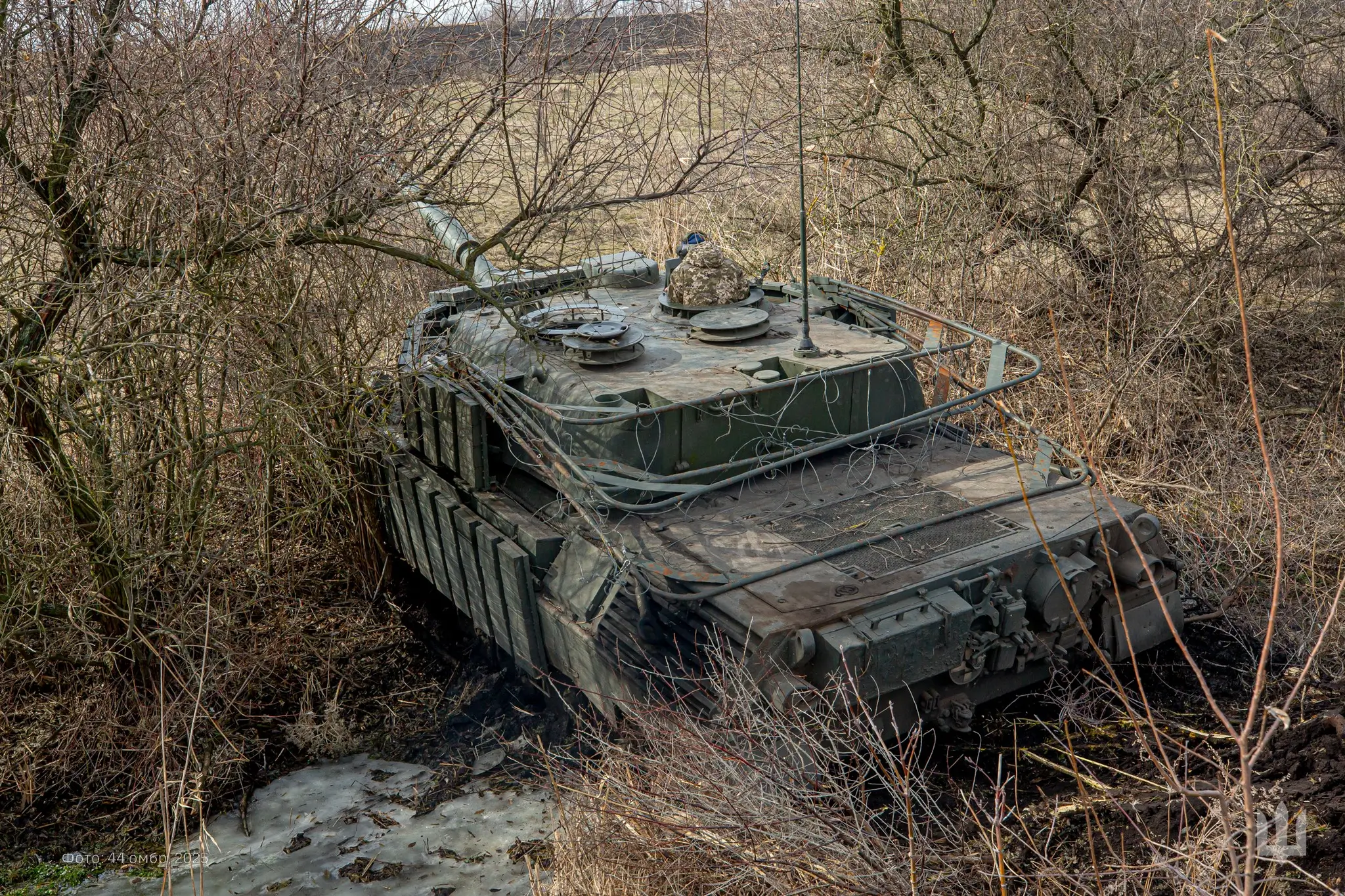 Leopard 1A5 with additional reactive armour and a drone cage drives through a ditch